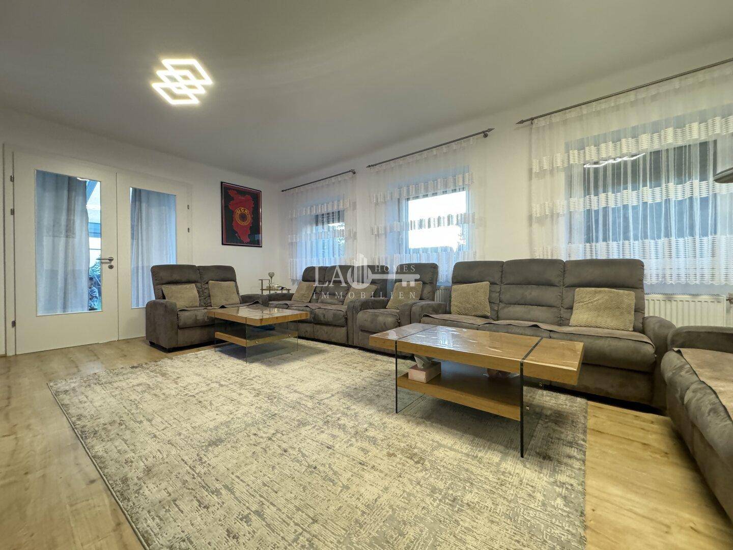Großzügiges Wohnzimmer mit bequemen Sofas, Teppich und großen Fenstern.