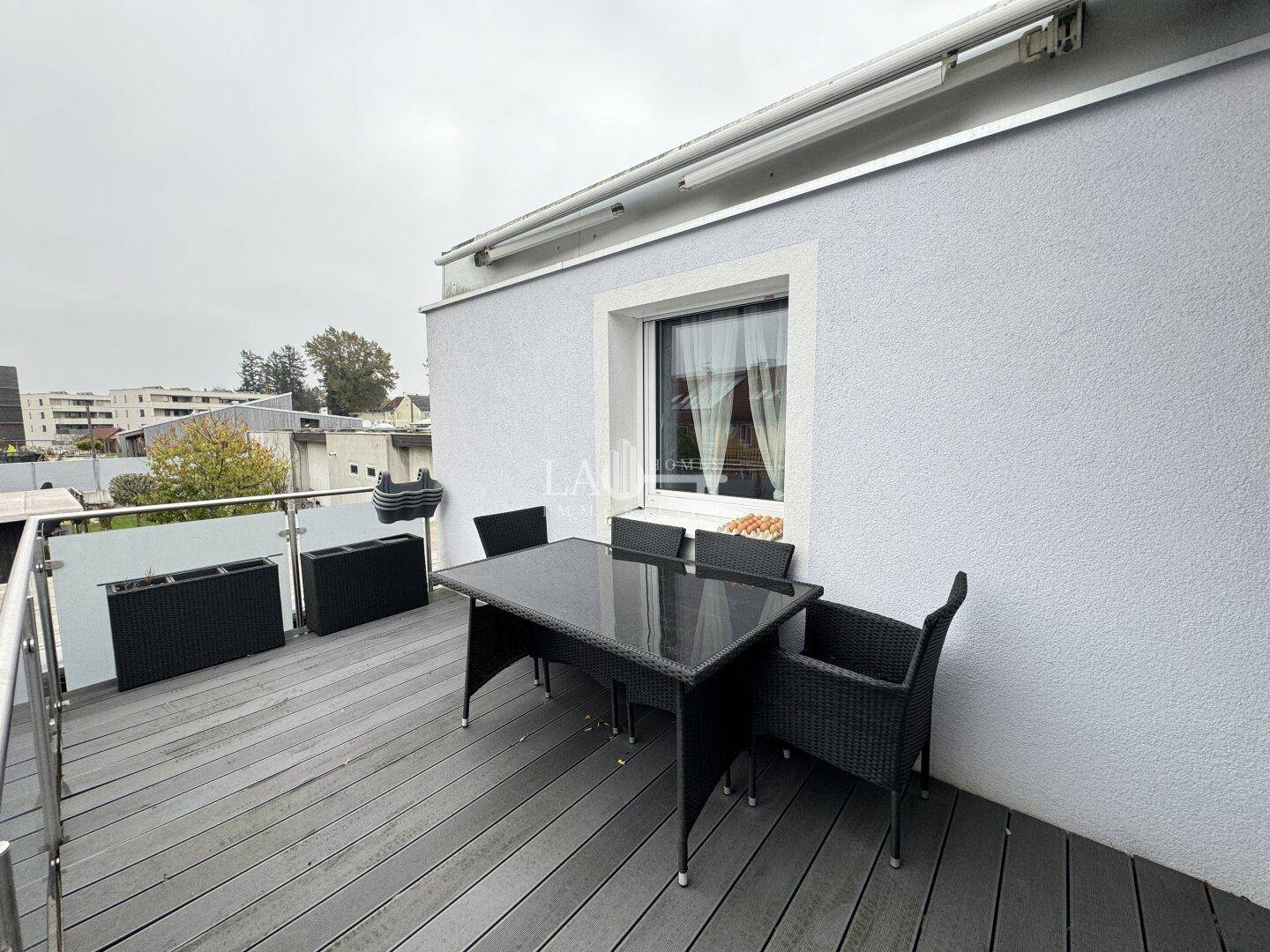 Balkon mit Holzboden und Outdoor-Möbeln, bietet Platz für gesellige Stunden im Freien.