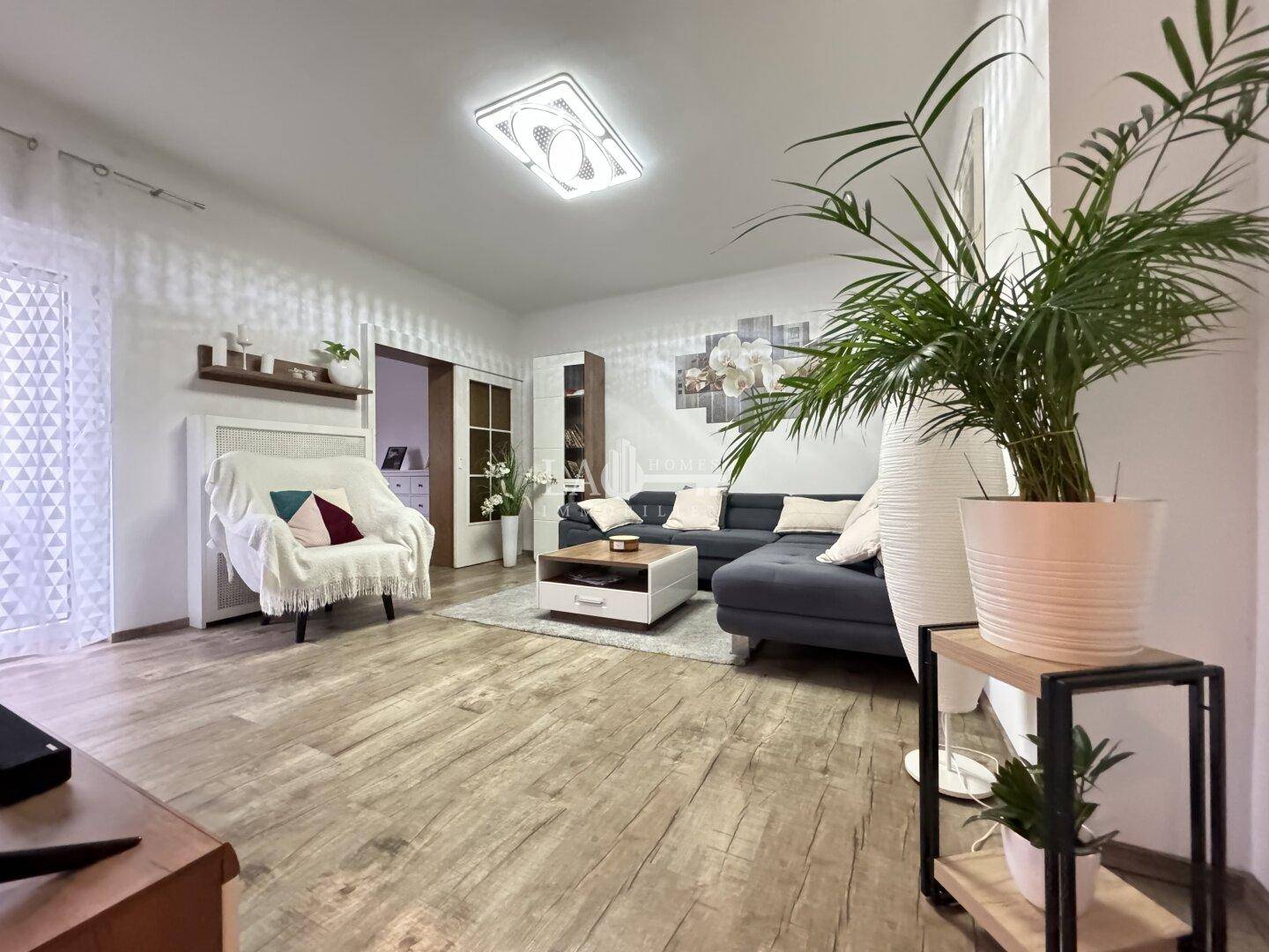 Gemütliches Wohnzimmer mit großem Ecksofa, modernem Dekor und hellem Laminatboden.