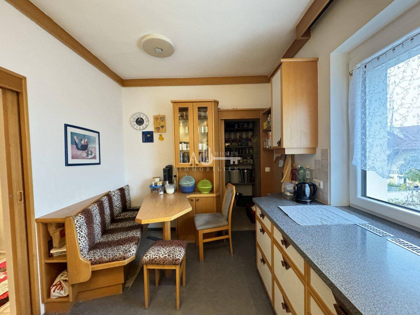 Küche mit gemütlicher Essecke, Holzschränken und Fenster, bietet viel Stauraum und Arbeitsfläche.
