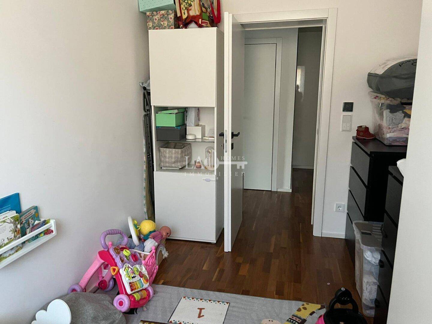 Kinderzimmer mit Spielzeug, Schrank und Holzboden.