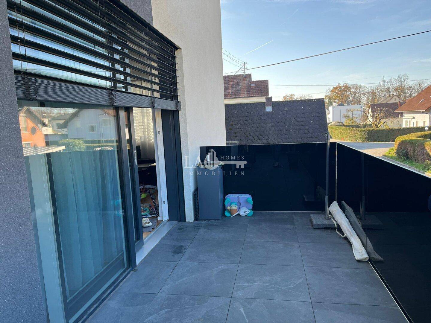 Moderne Terrasse mit großen Fliesen und Schiebetür zum Innenbereich.