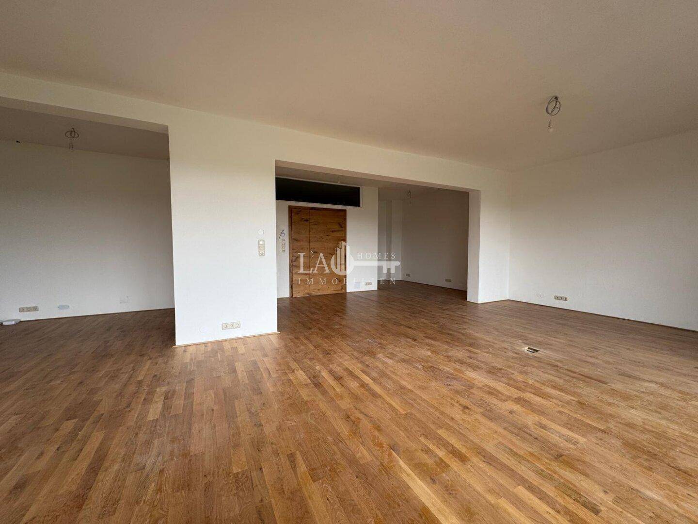Heller, leerer Wohnbereich mit Holzboden und einem Durchgang zu einem weiteren Raum, ideal für eine offene Gestaltung.