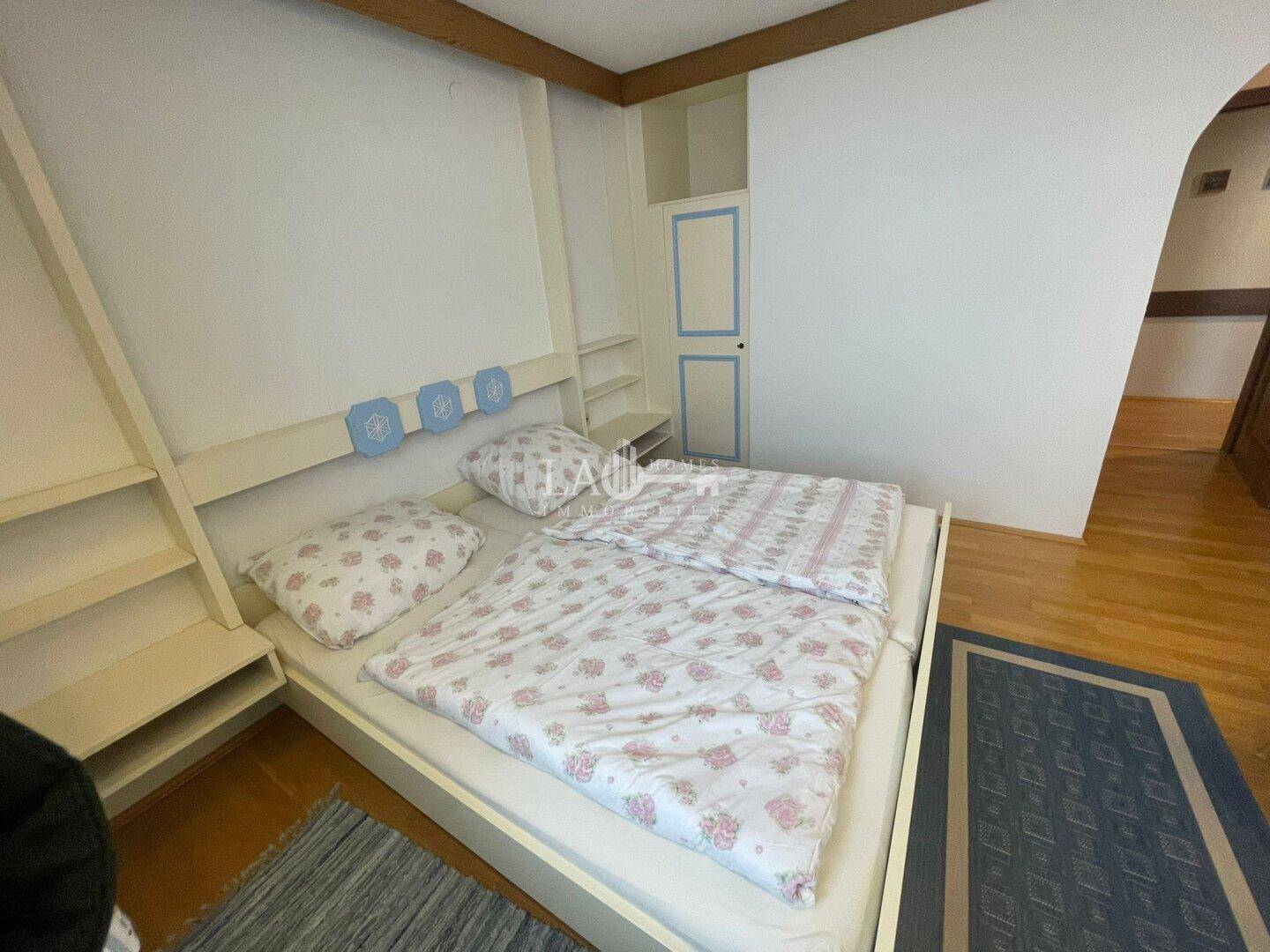 Schlafzimmer mit Doppelbett, Holzboden und einem Einbauschrank in heller Farbgebung.
