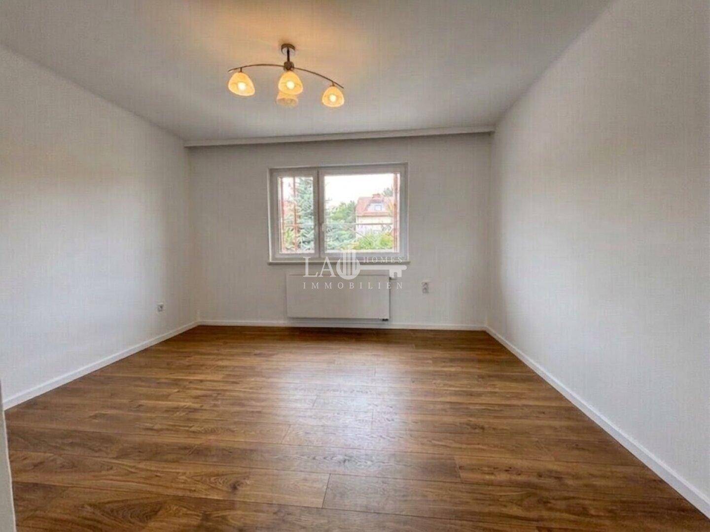 Geräumiges, helles Zimmer mit Laminatboden und großem Fenster, ideal als Wohn- oder Schlafzimmer.