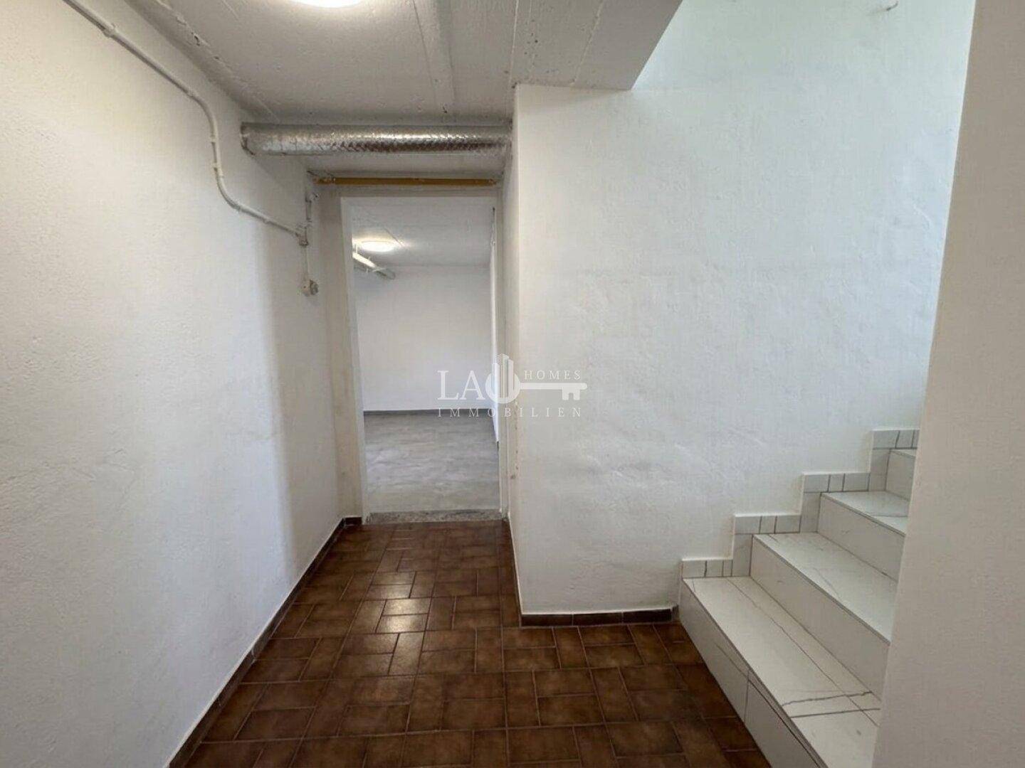 Kellerflur mit gefliestem Boden und Zugang zu weiteren Kellerräumen, praktisch und geräumig.