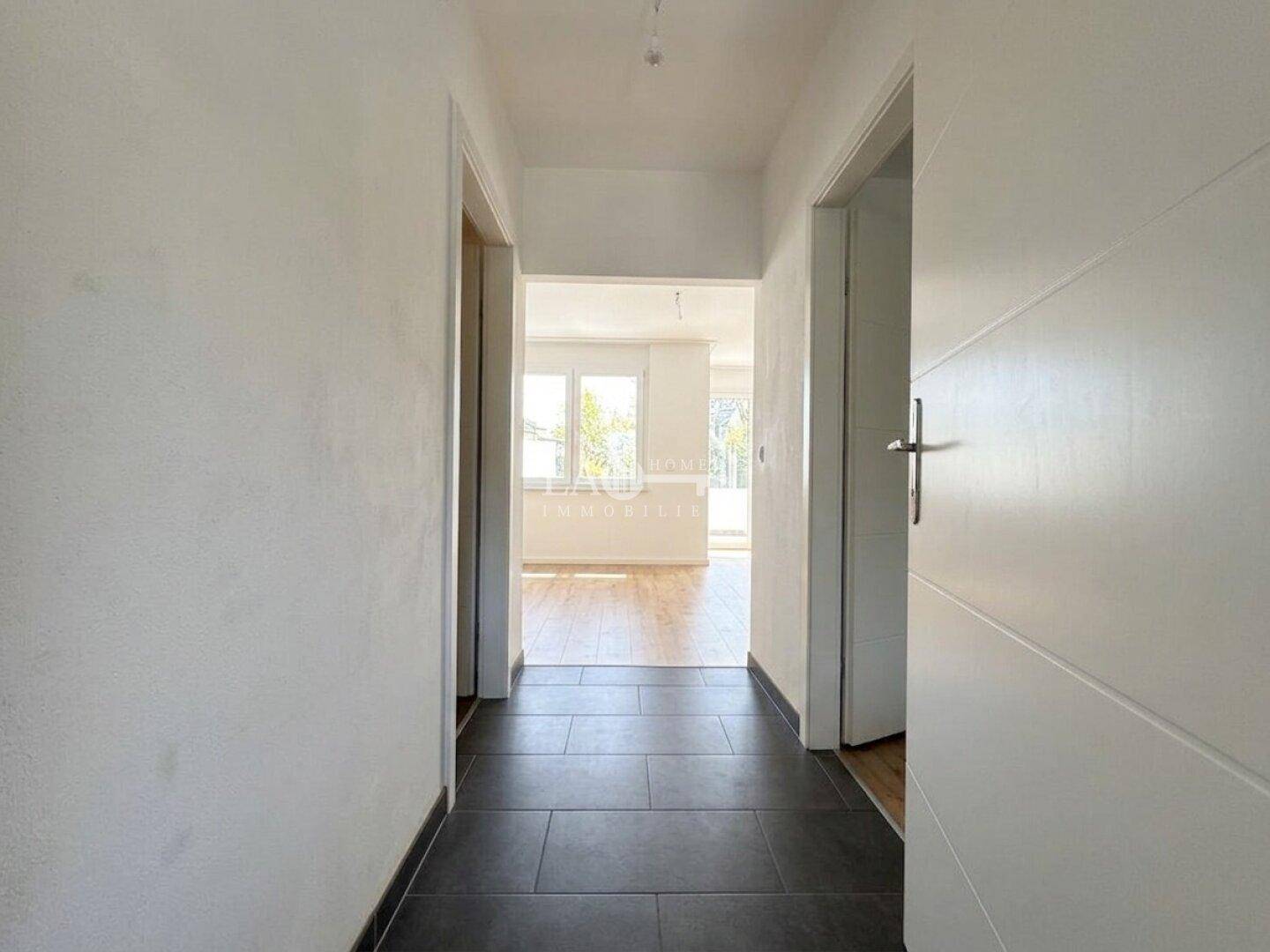 Heller Flur mit dunklen Fliesen und Zugang zu weiteren Zimmern der Wohnung.