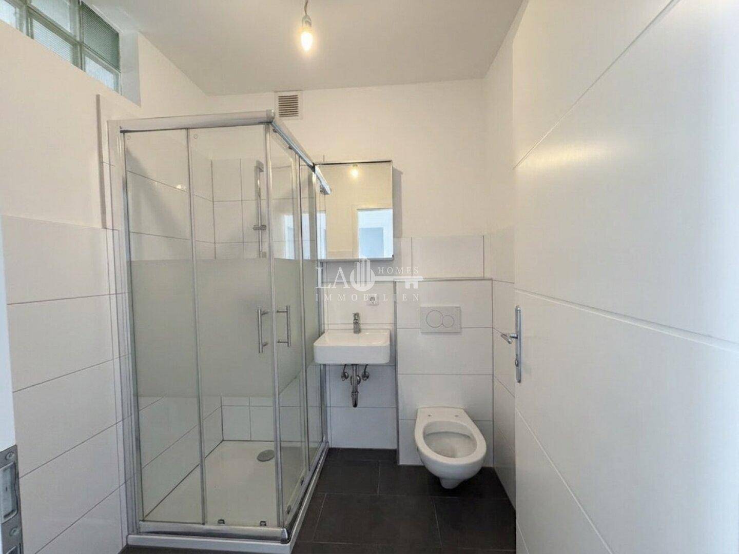 Modernes Badezimmer mit Duschkabine, WC, Waschbecken und weißen Fliesen.