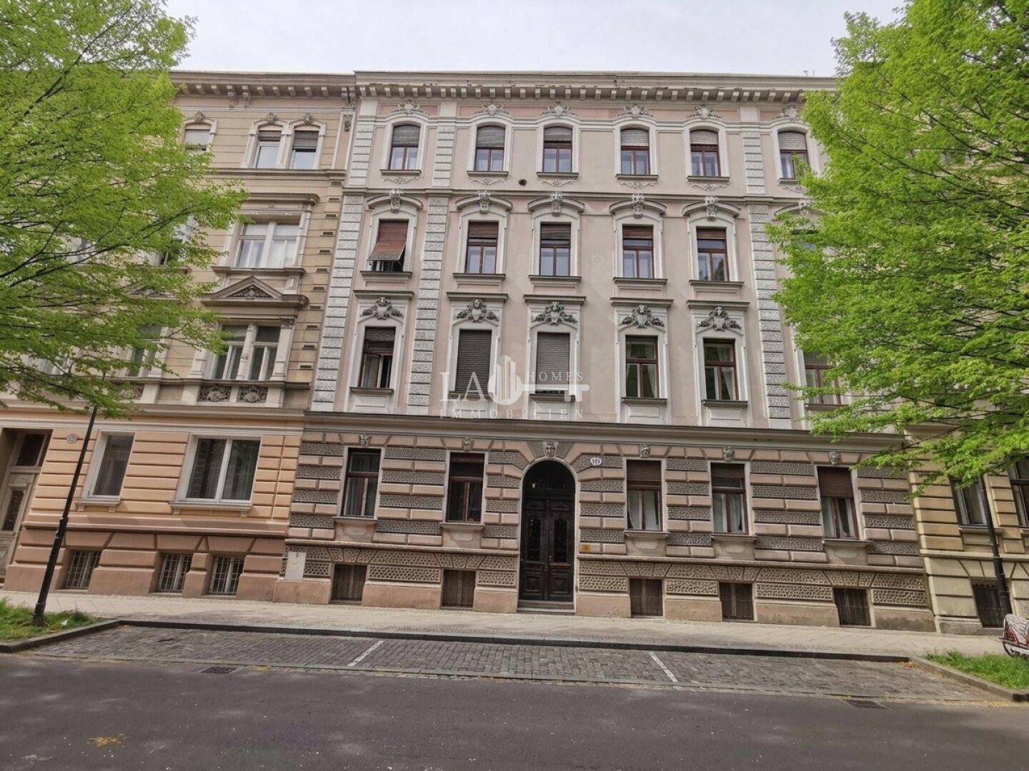 Detailansicht der reich verzierten Fassade eines Altbaus mit vielen Fenstern und klassischer Architektur.