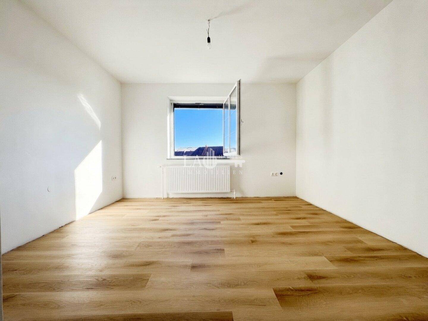 Geräumiger, heller Raum mit Laminatboden und einem Fenster, das einen weiten Blick bietet.