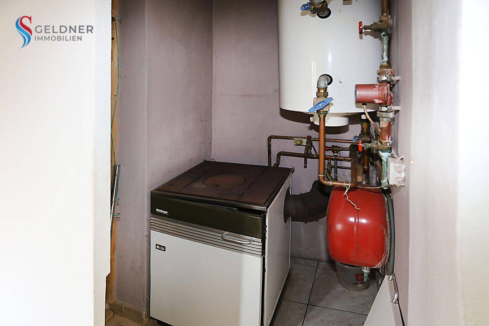 Heizraum mit Boiler, Rohren und einem alten Holzofen.