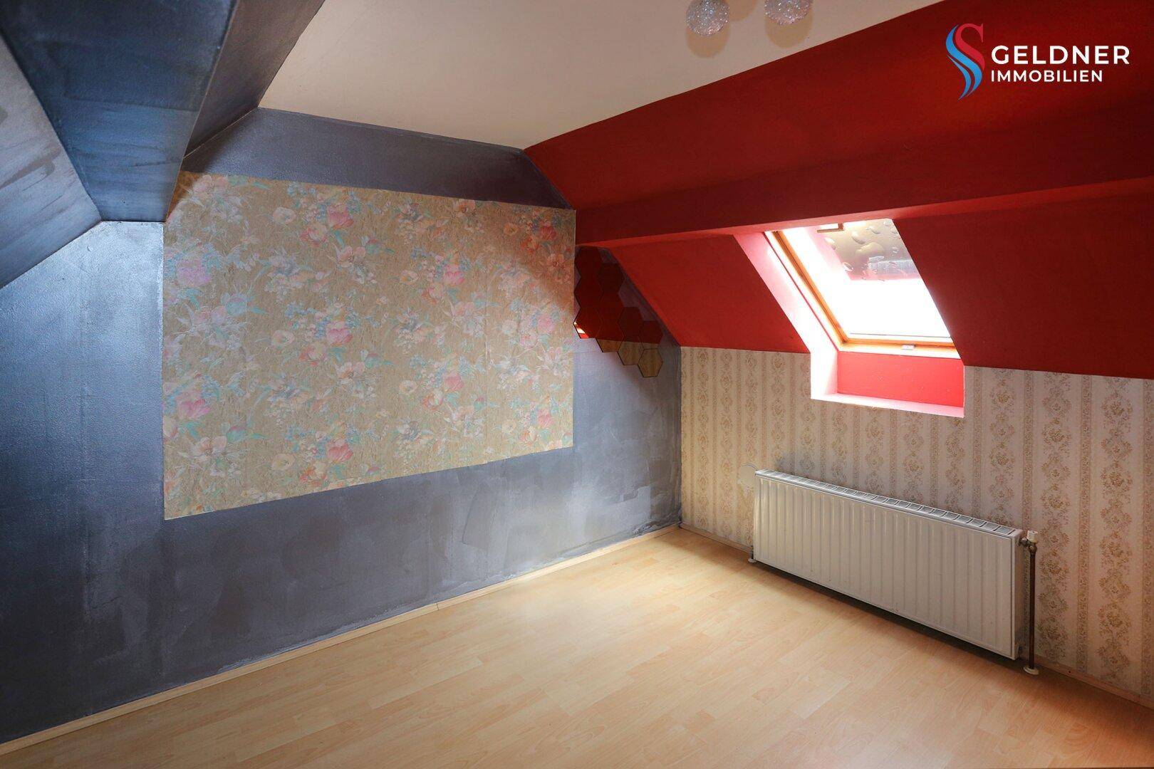 Schlafzimmer im Dachgeschoss mit schrägen Wänden, Dachfenster und Laminatboden.