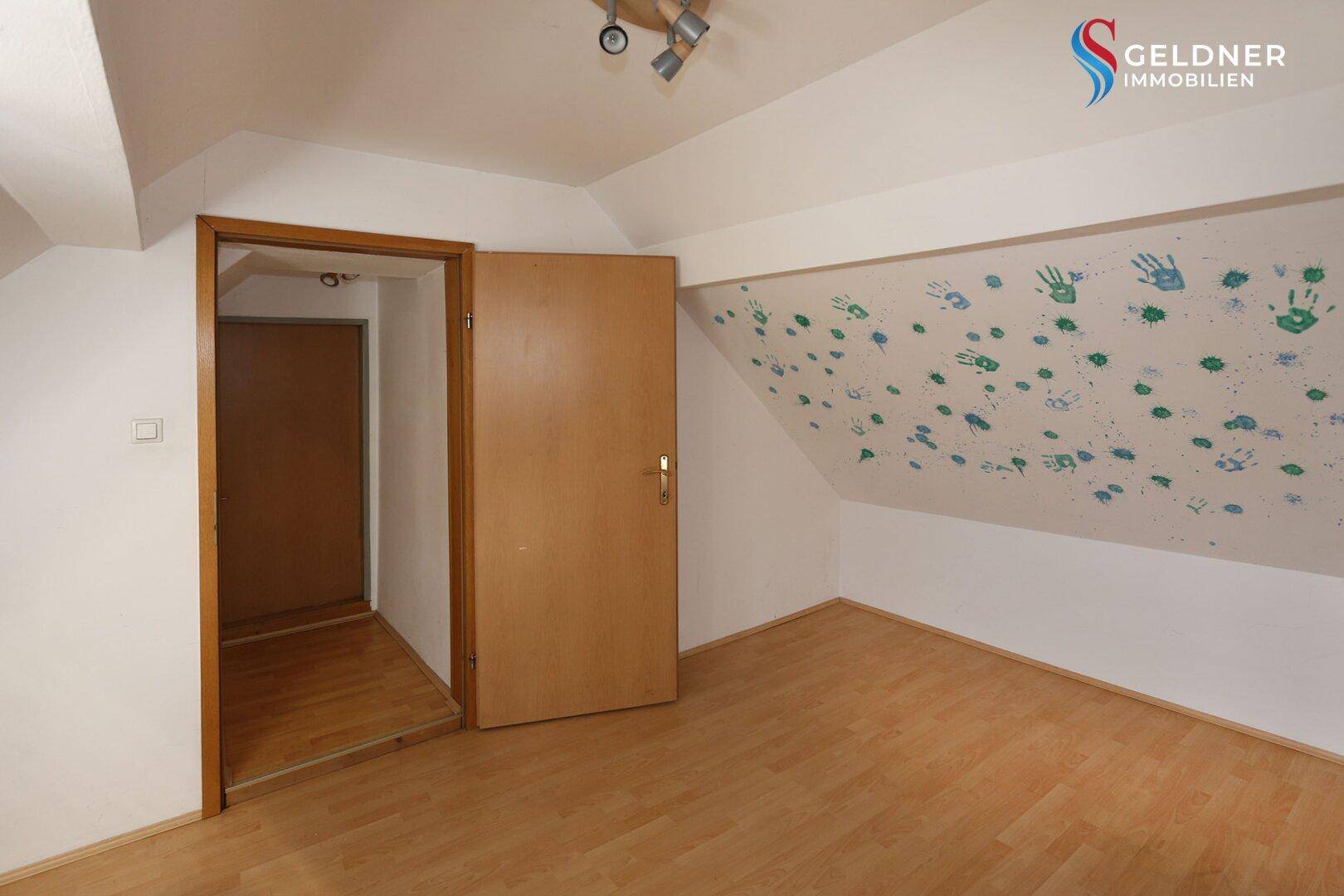 Dachgeschosszimmer mit Laminatboden, schrägen Wänden und kreativer Wandgestaltung.