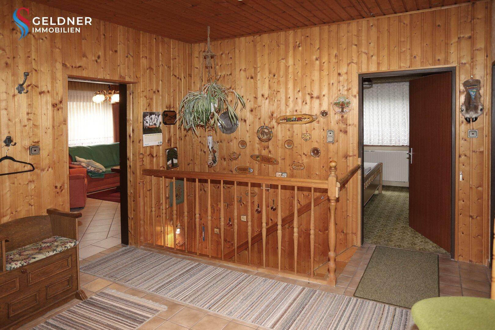 Rustikaler Flur mit Holzvertäfelung, Treppe und Zugang zu weiteren Räumen.