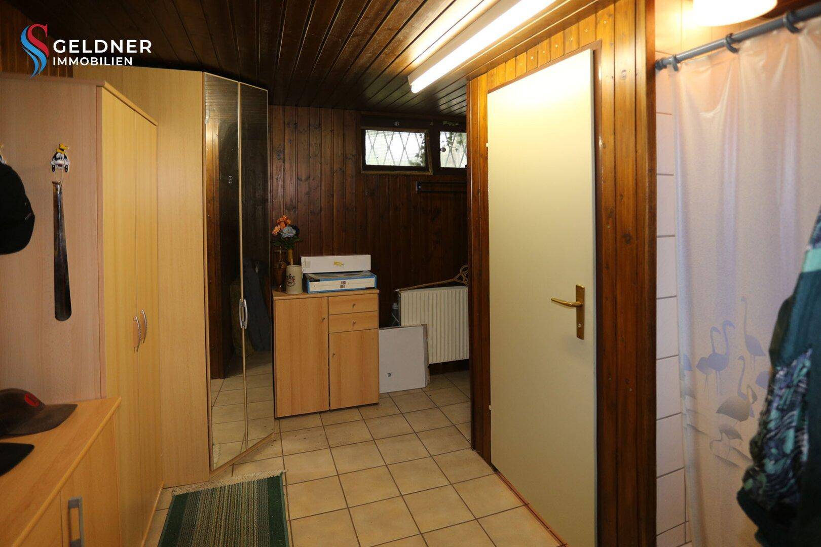 Kellerraum mit Holzvertäfelung, Fliesenboden und Stauraum.