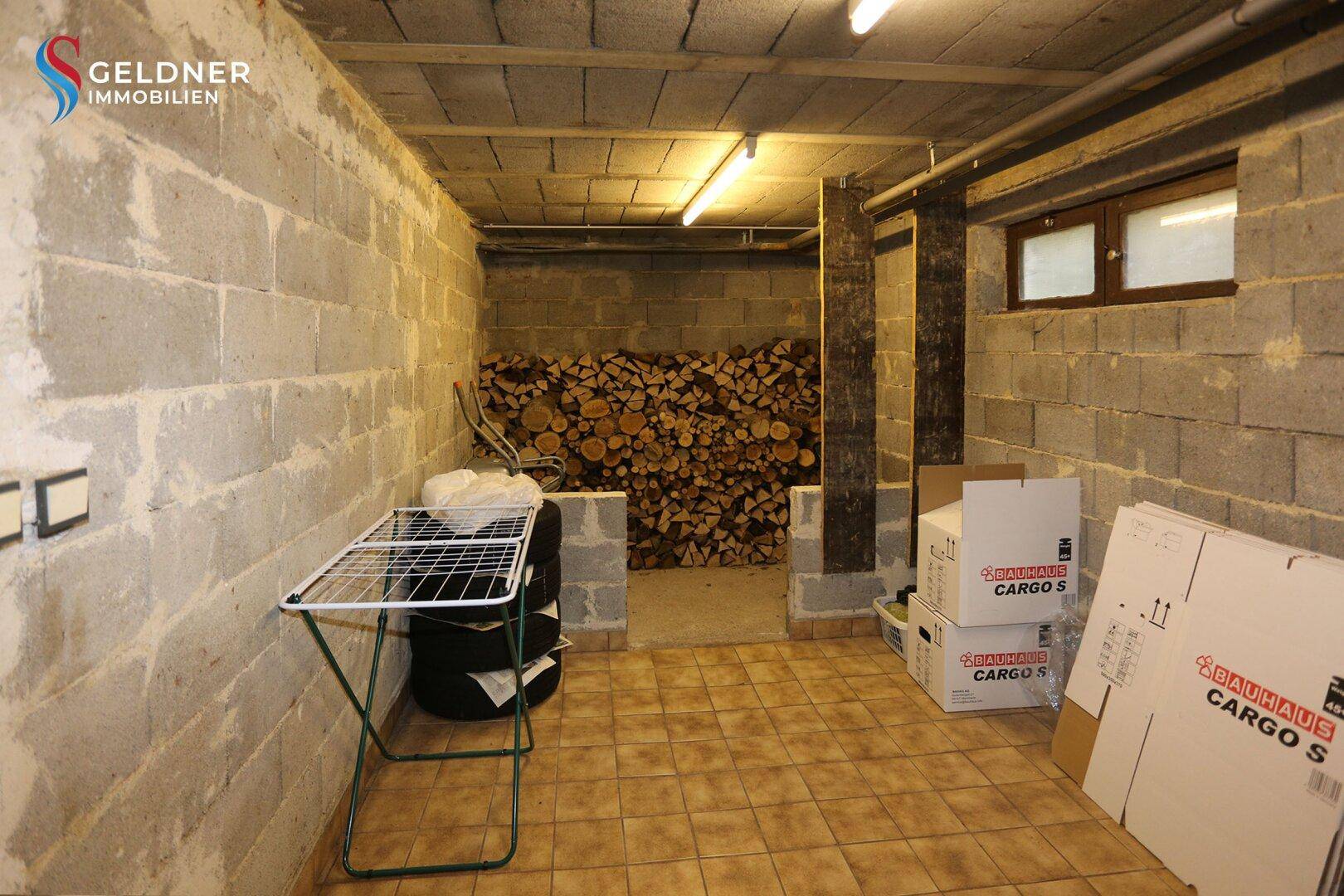 Geräumiger Lagerraum im Keller mit gestapeltem Brennholz und Fliesenboden.