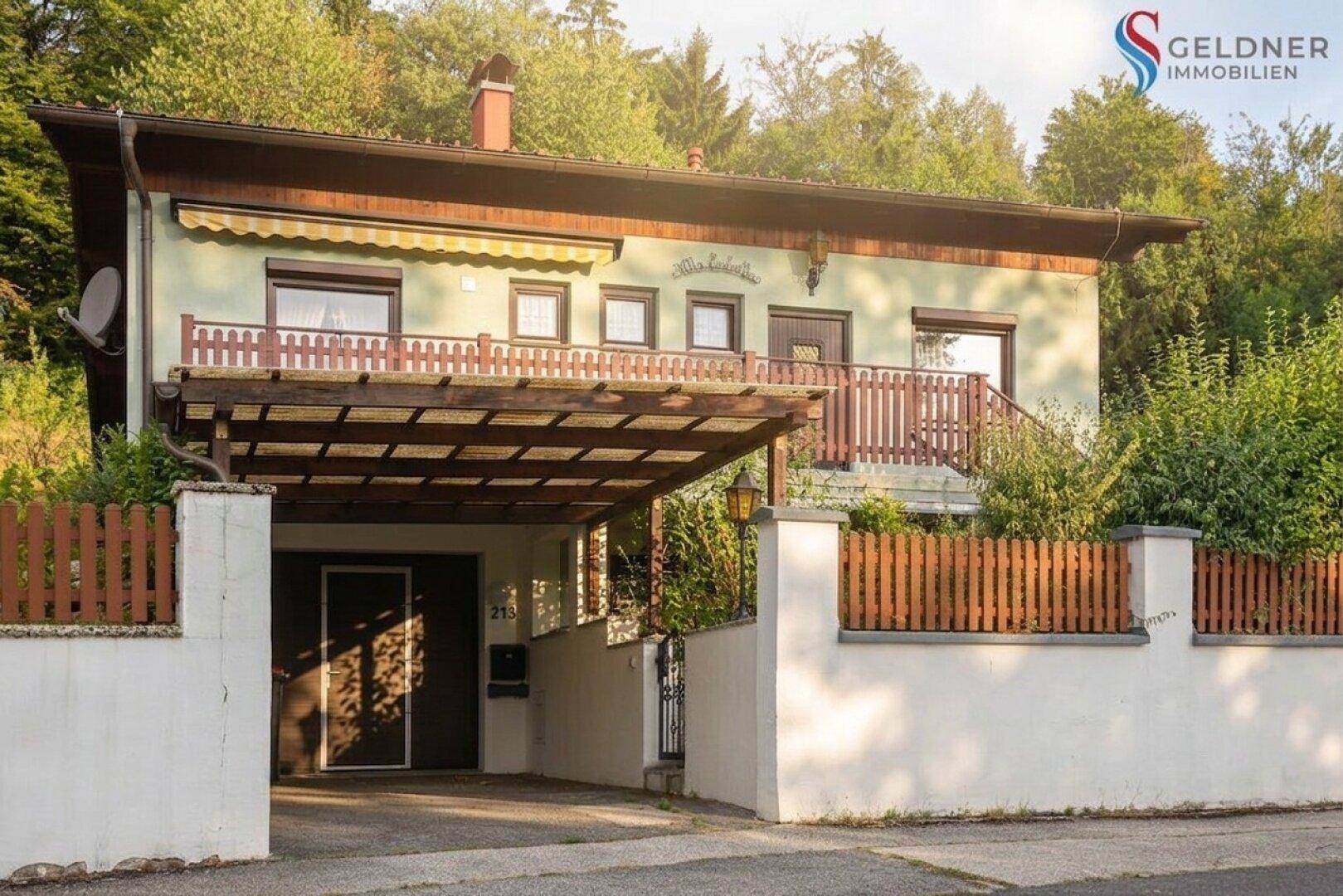 Vorderansicht des Hauses mit Carport, Balkon und gepflegtem Eingangsbereich.