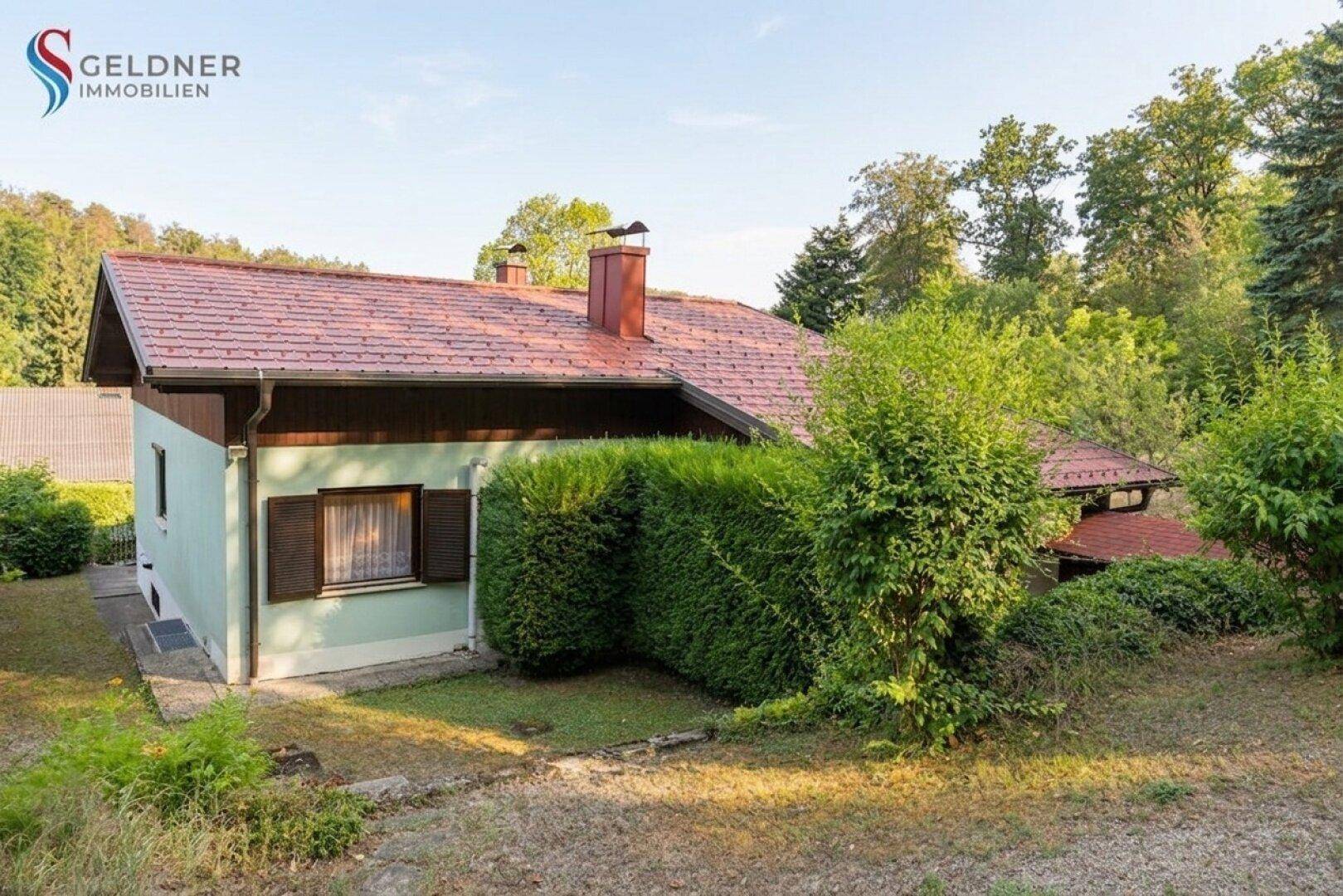 Seitenansicht des Hauses mit Satteldach und gepflegter Hecke im Gartenbereich.