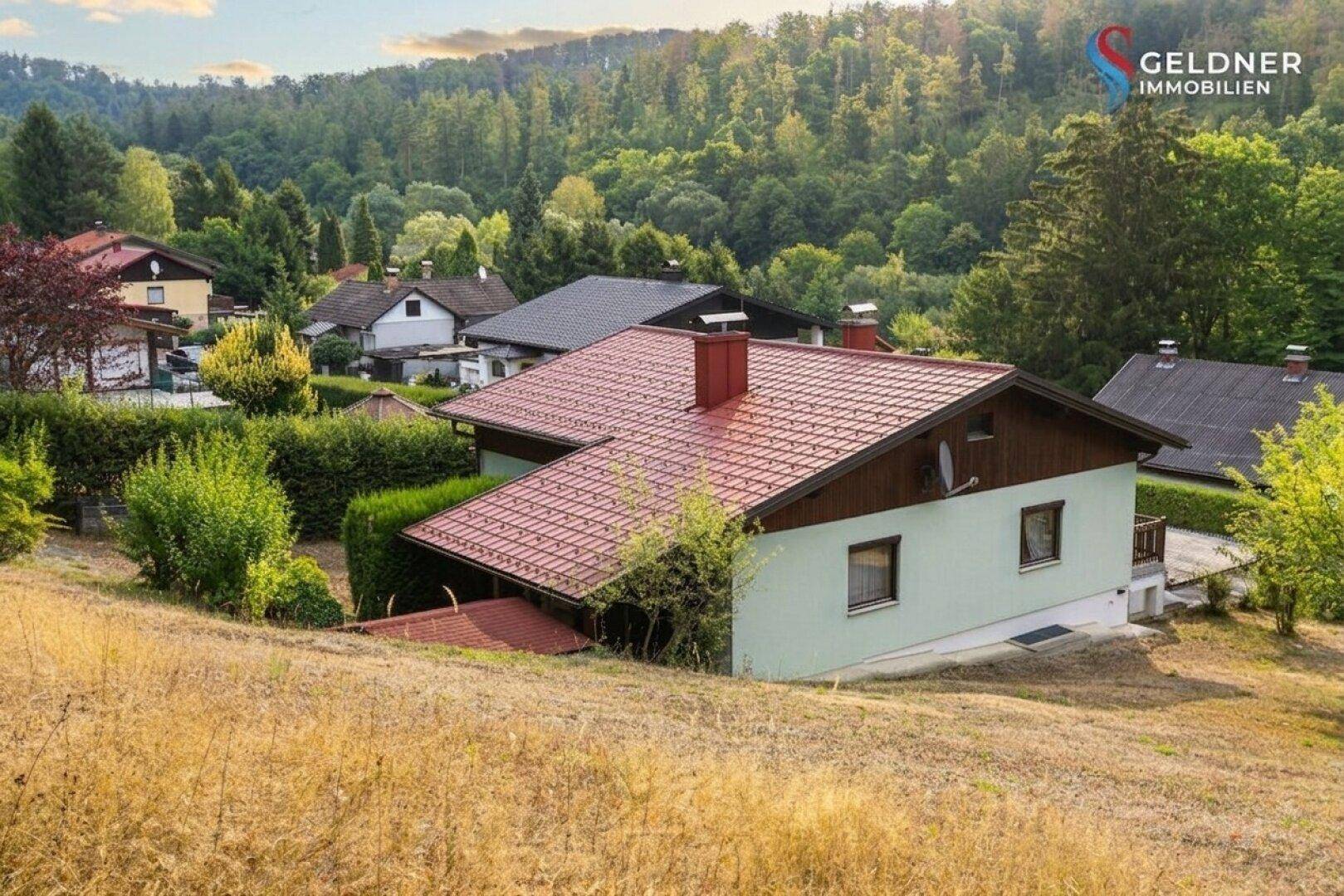 Panoramablick auf das Haus in ländlicher Umgebung mit bewaldeten Hügeln im Hintergrund.