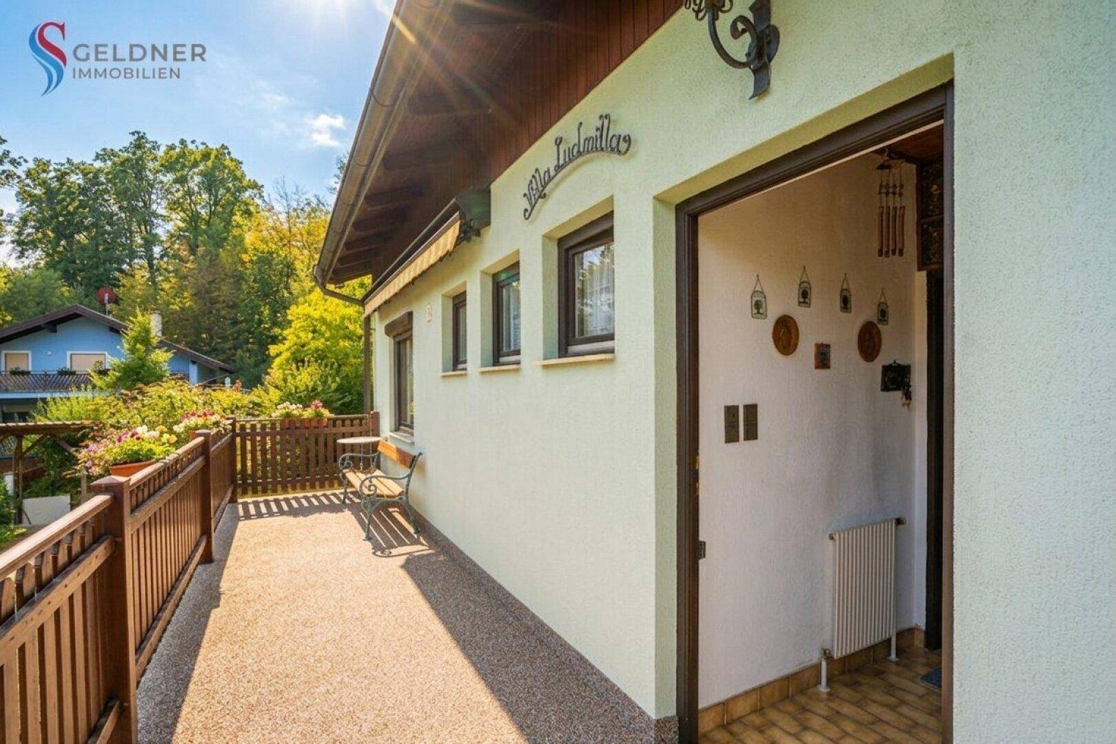 Schmaler Balkon mit Holzzaun und Sitzbank, direkt am Hauseingang gelegen.