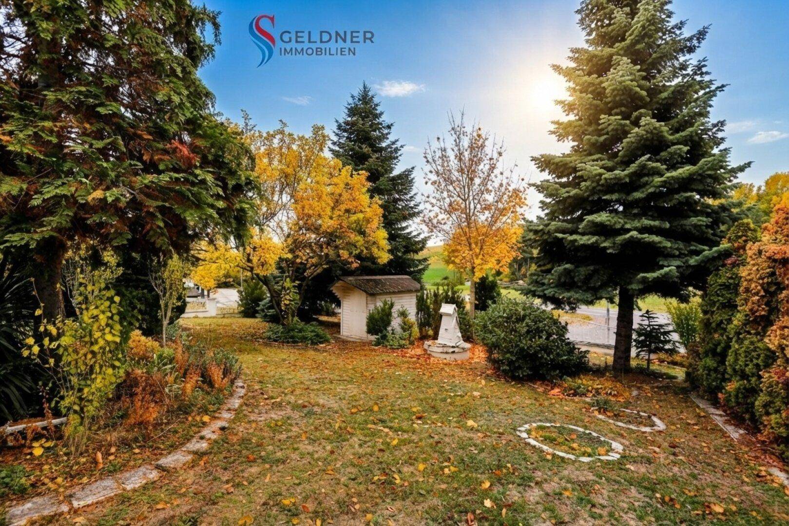Großer, gepflegter Garten mit Rasenfläche, Bäumen und einem kleinen Gartenhaus im Herbst.