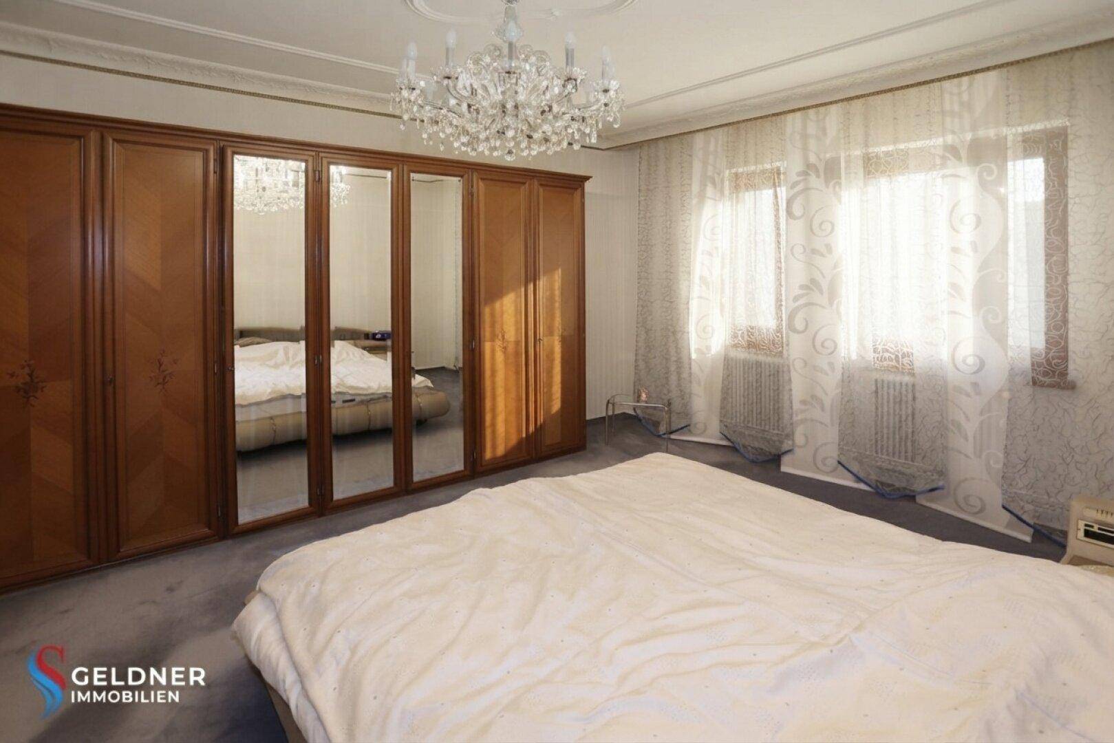 Schlafzimmer mit großem Kleiderschrank mit Spiegeltüren und einem Doppelbett in traditionellem Design.