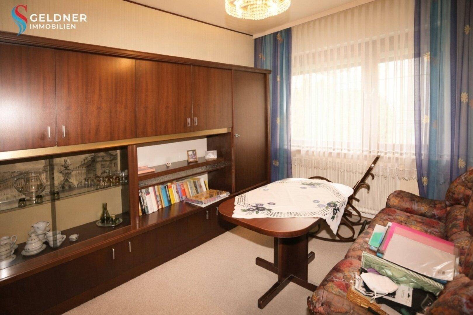 Wohnzimmer mit großem Holzschrank, Sofa und Tisch, in einem traditionellen Ambiente mit viel Stauraum.