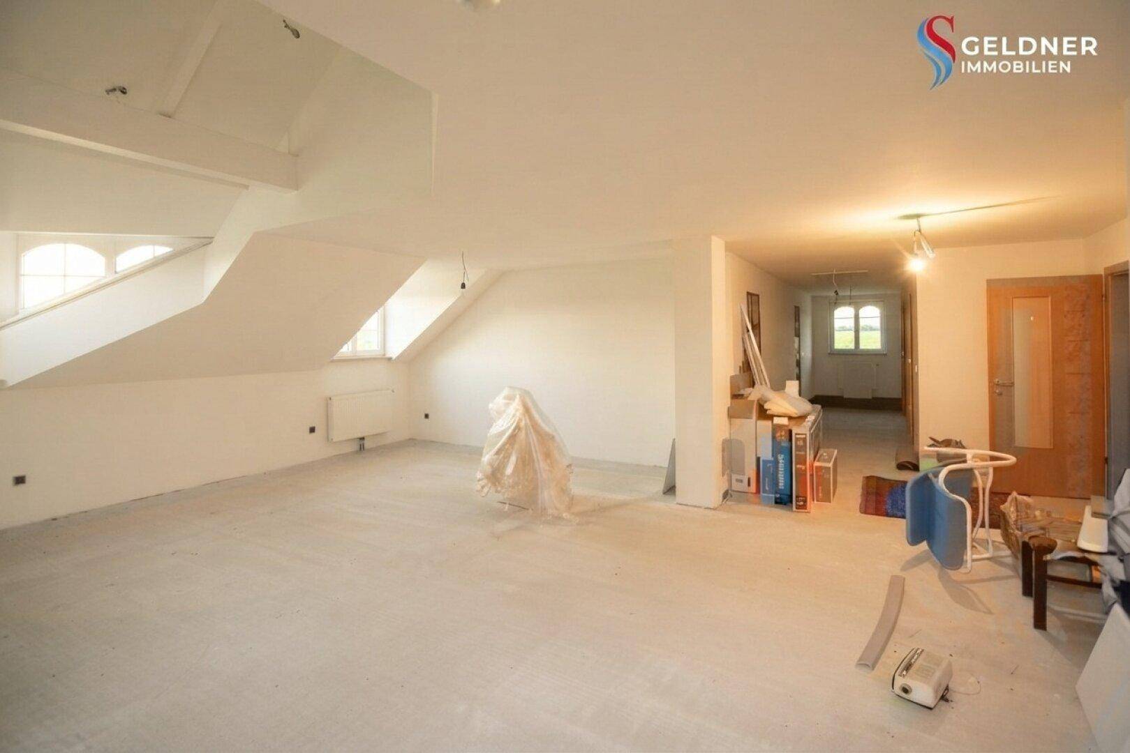 Weiter Dachbodenraum mit schrägen Wänden und Fenstern, bietet viel Potenzial für Wohnraum.