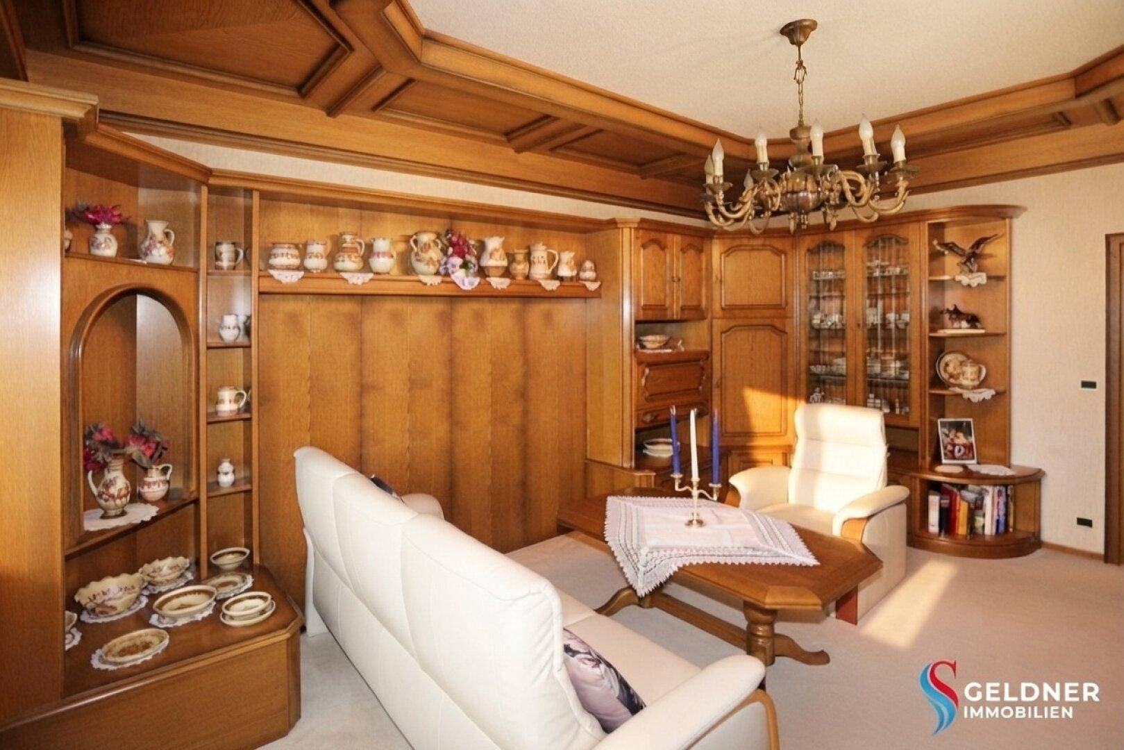 Wohnzimmer mit Holzeinbauten, Ledersofa und dekorativen Elementen, hell und gepflegt.