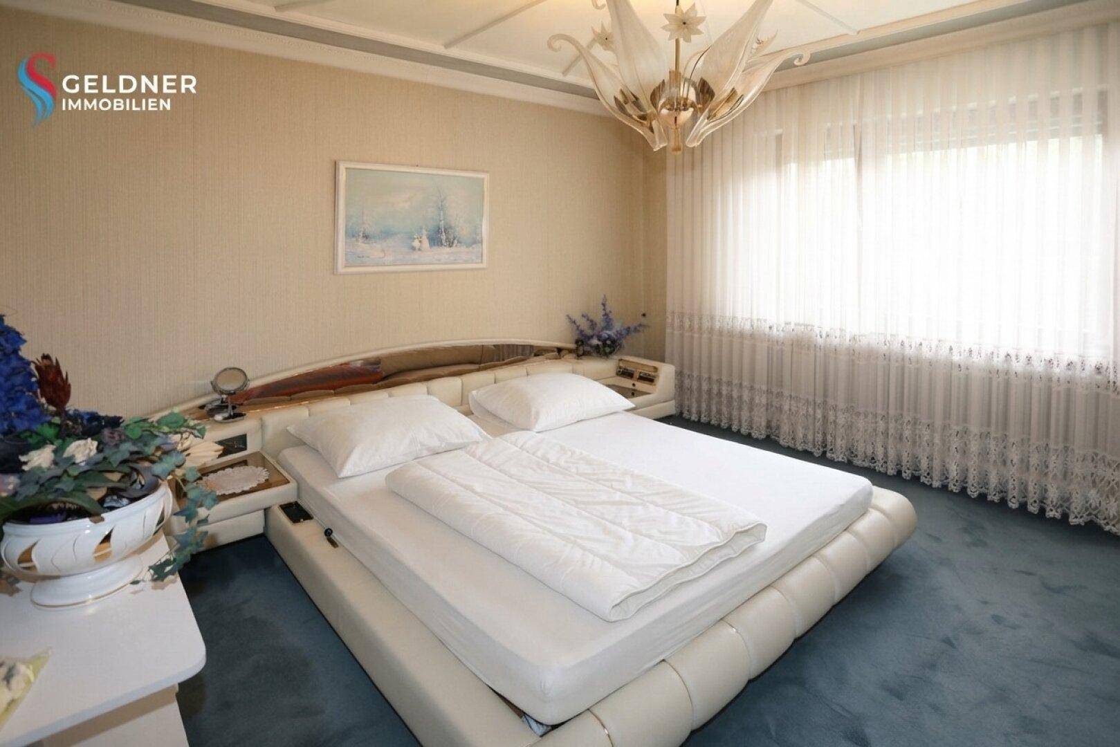 Helles Schlafzimmer mit Doppelbett, dekorativer Beleuchtung und großen Fenstern mit Vorhängen.