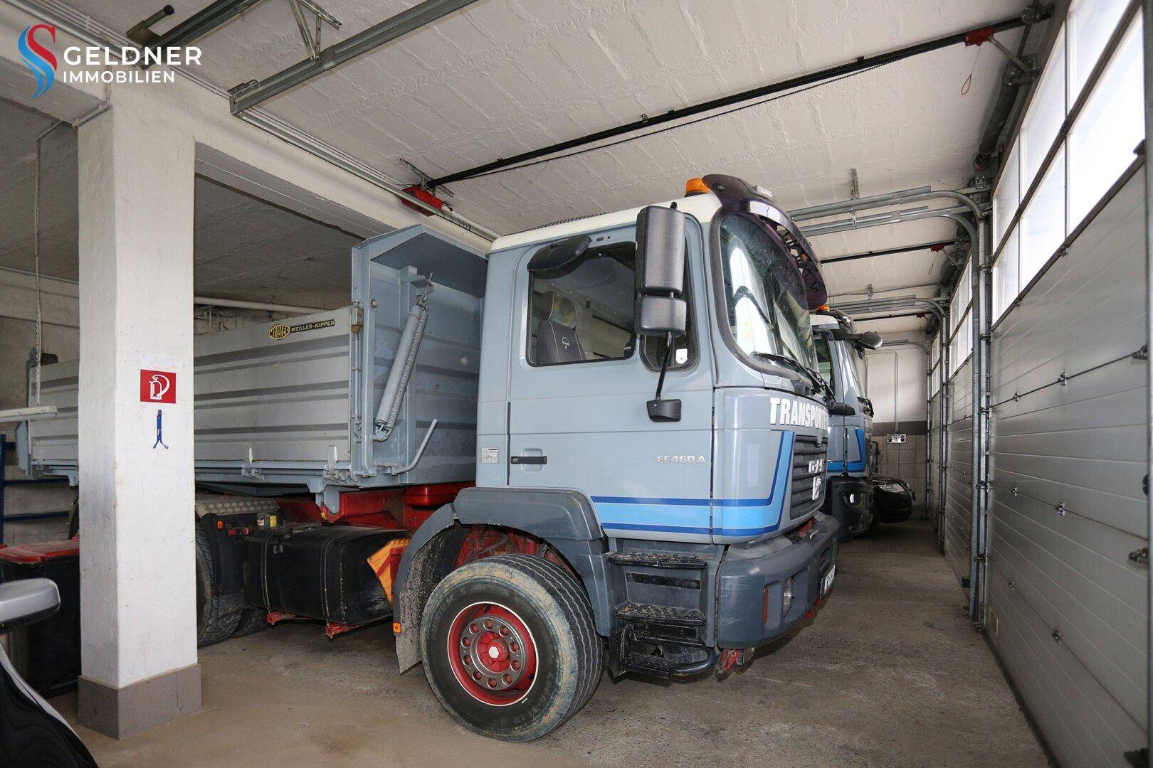 Große Garage mit mehreren Lastwagen und Rolltoren, bietet viel Platz für Fahrzeuge.