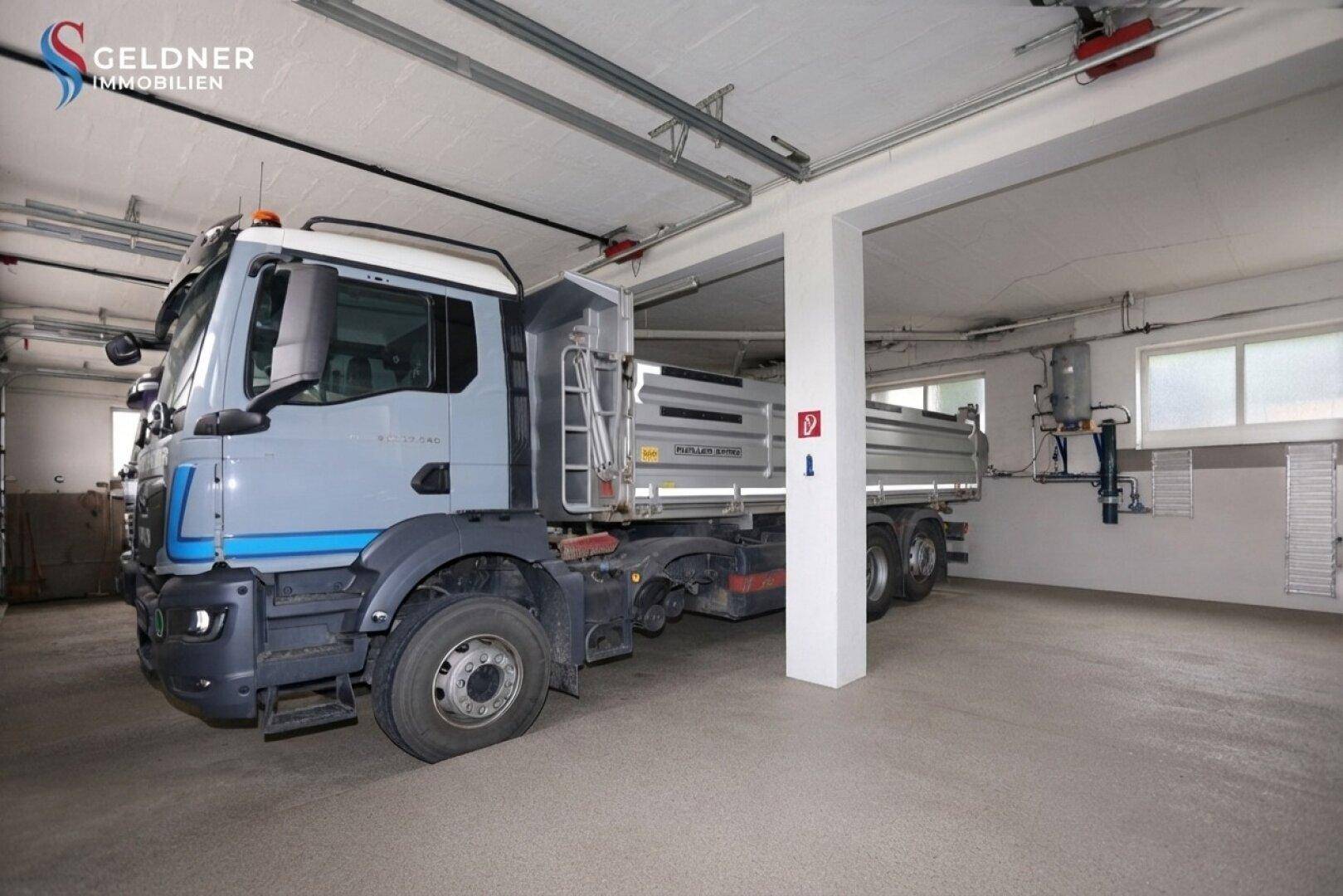 Geräumige Garage mit ausreichend Platz für große Fahrzeuge und Tageslichtfenstern.