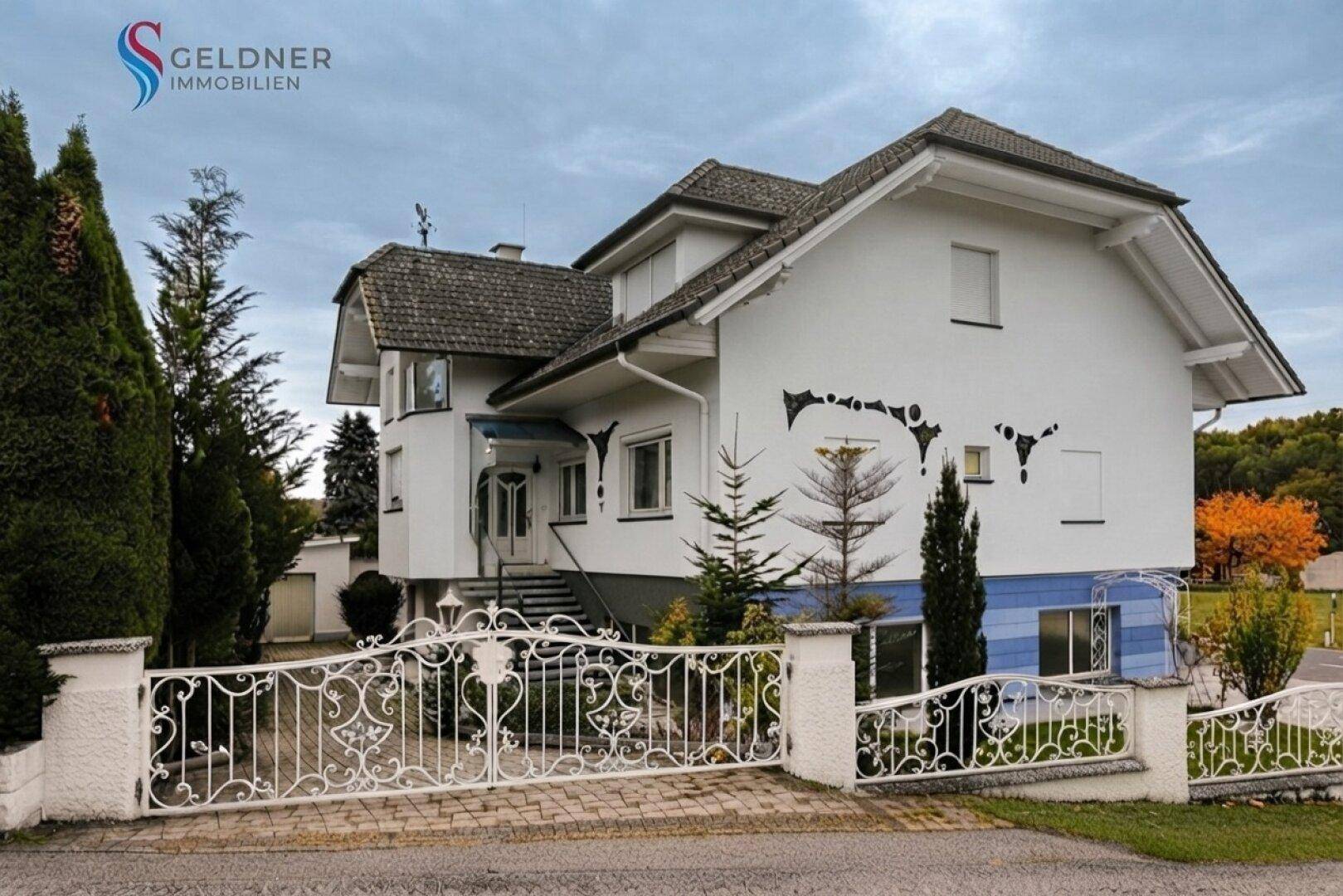 Seitenansicht des Hauses mit Eingangsbereich, Treppe und dekorativem schmiedeeisernem Zaun.