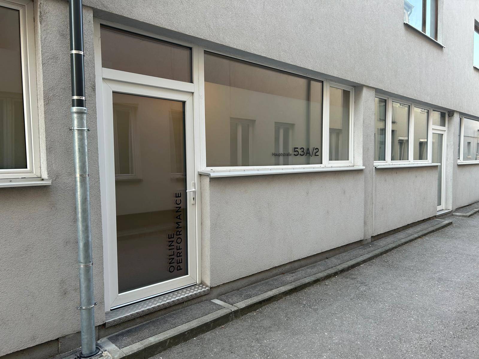 Außenansicht eines modernen Geschäftsgebäudes mit großen Fenstern und einem barrierefreien Eingang.