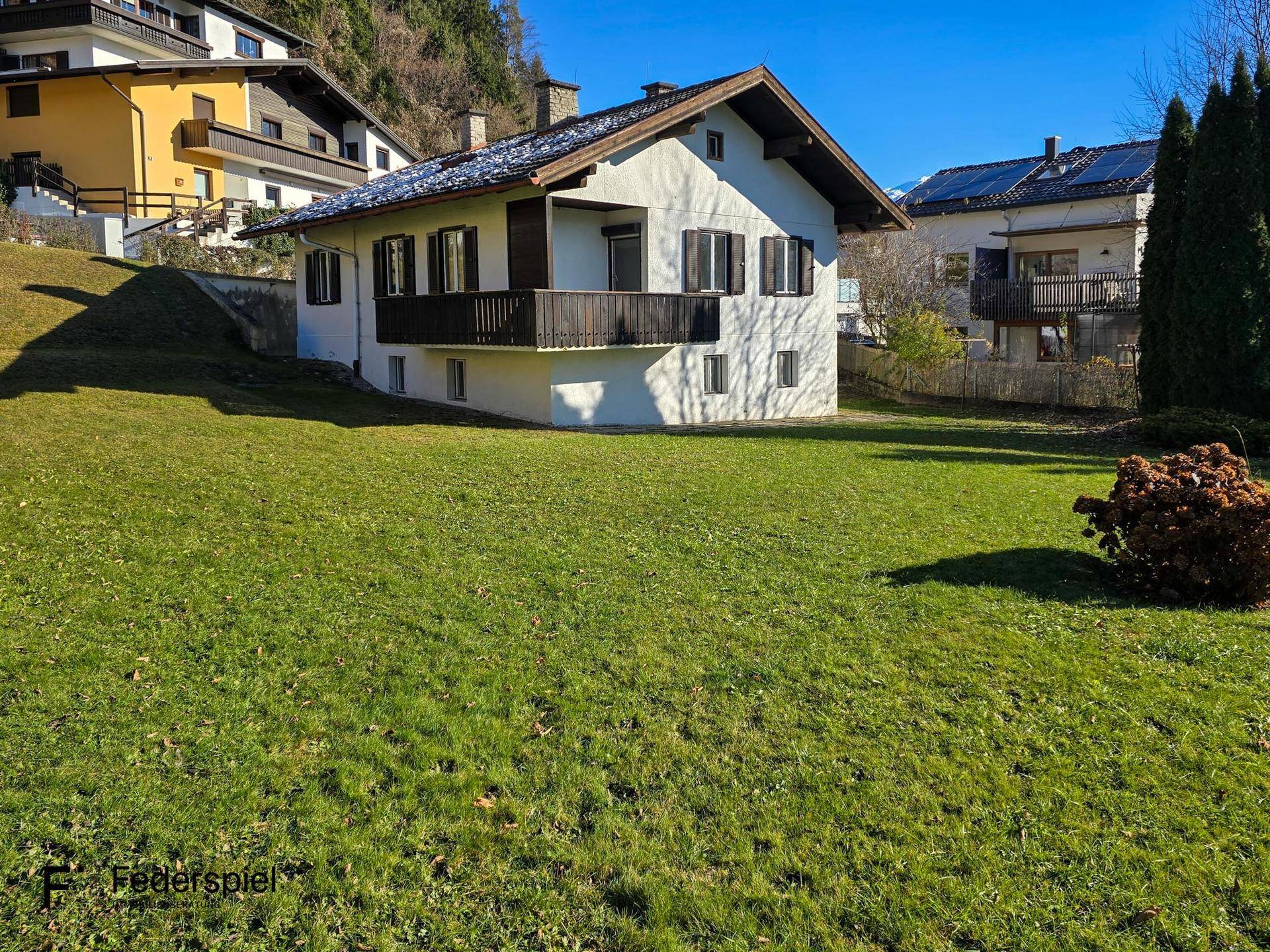 Charmantes Haus mit großem, sonnigen Garten und traditioneller Architektur in alpiner Umgebung.
