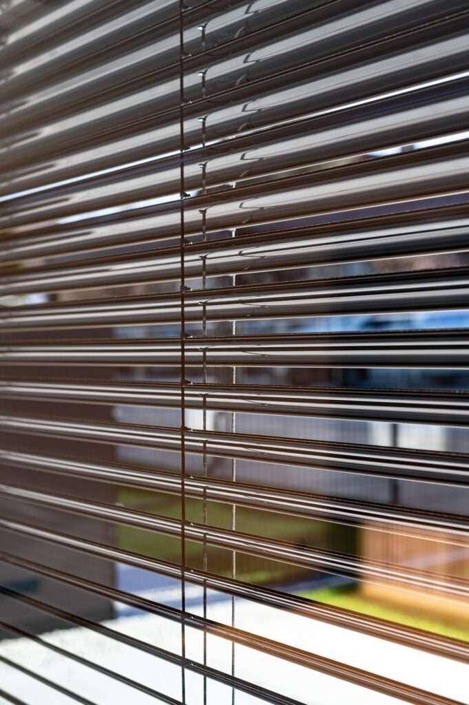 Nahaufnahme von modernen Jalousien vor einem Fenster, die Licht und Privatsphäre regulieren.