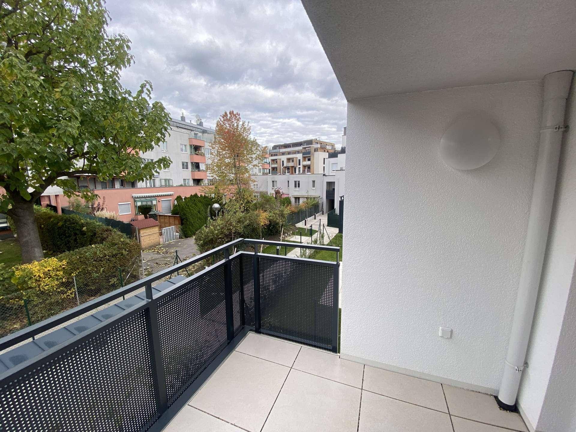 Balkon mit Fliesenboden und Blick auf die umliegende Wohngegend mit Bäumen und Gebäuden.