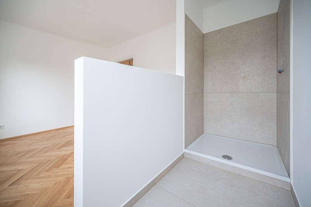 Modernes Badezimmer mit begehbarer Dusche und hellen Fliesen, bereit zur Fertigstellung.