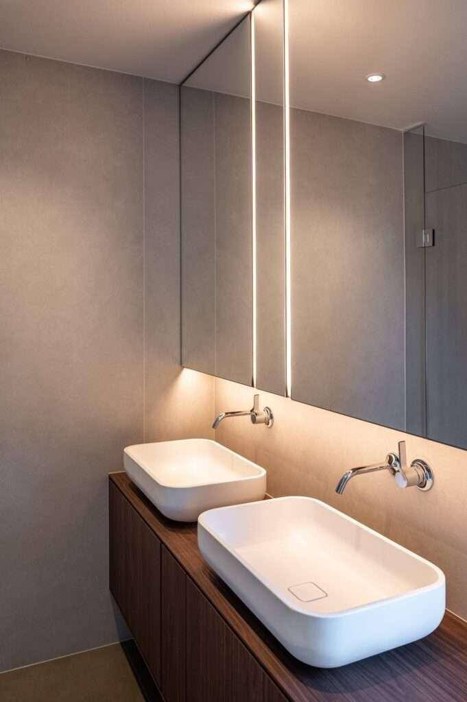 Nahaufnahme eines modernen Doppelwaschbeckens mit integrierter Spiegelbeleuchtung im Badezimmer.