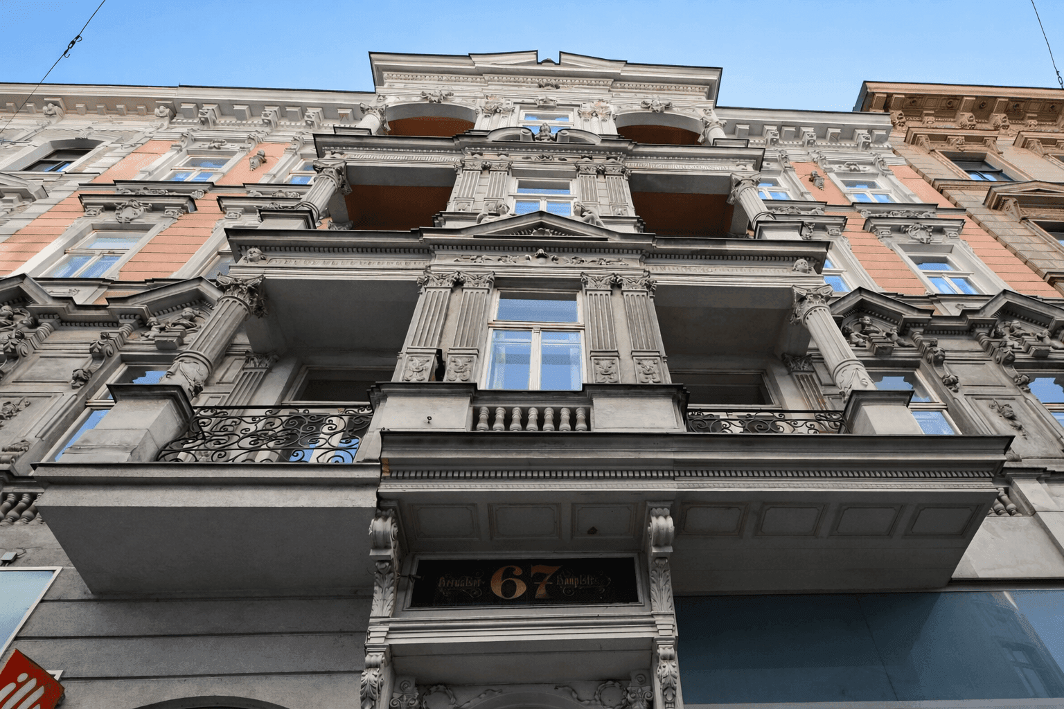 Historische und reich verzierte Fassade eines Altbaus mit Balkonen und Säulen.