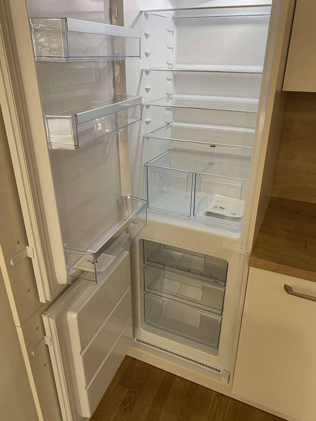 Offener Kühlschrank mit Gefrierfach, sauber und unbenutzt, als Teil der modernen Einbauküche.