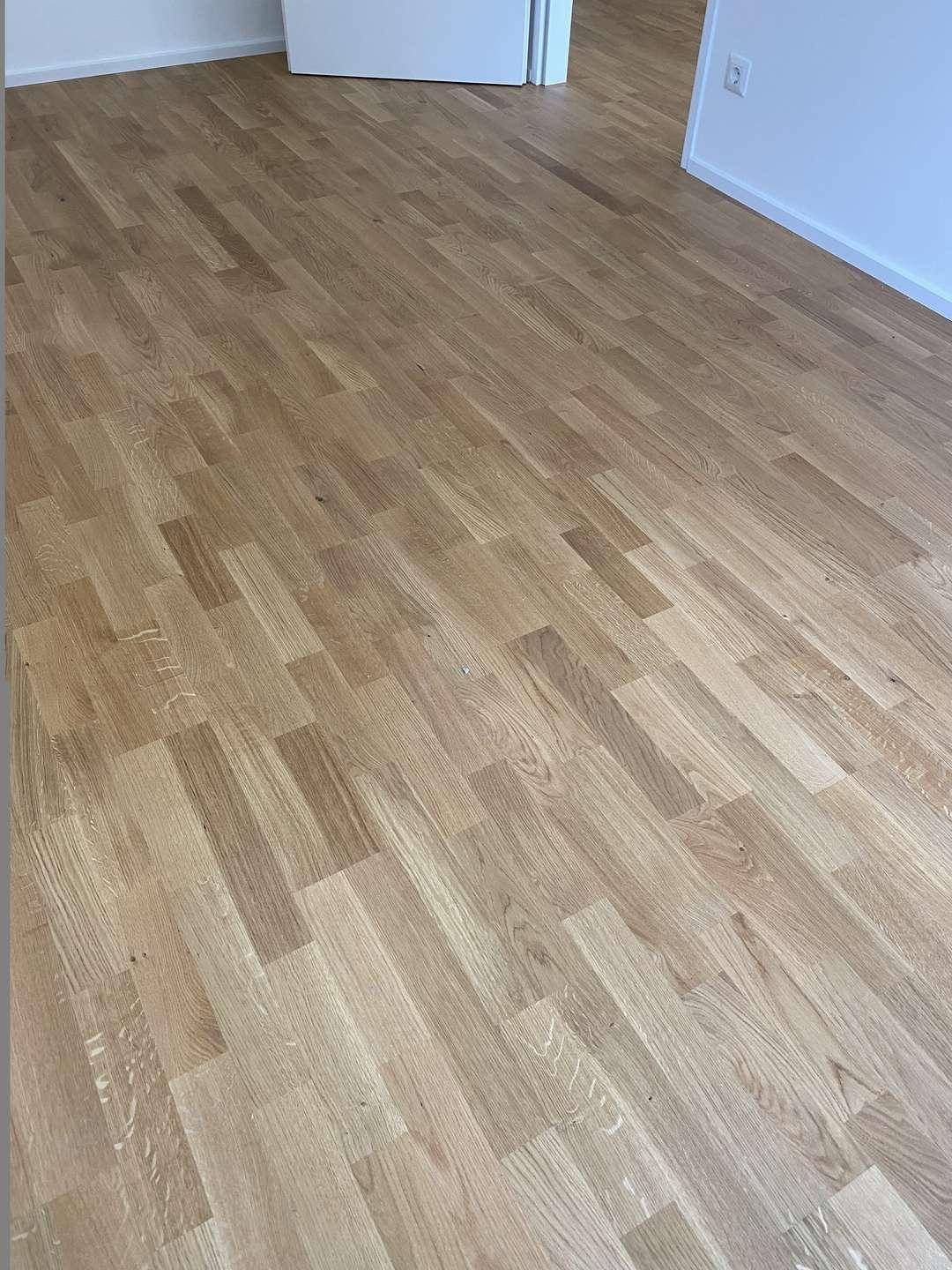 Detailaufnahme des hellen Holzparkettbodens in einem neuwertigen Zustand, frisch verlegt.