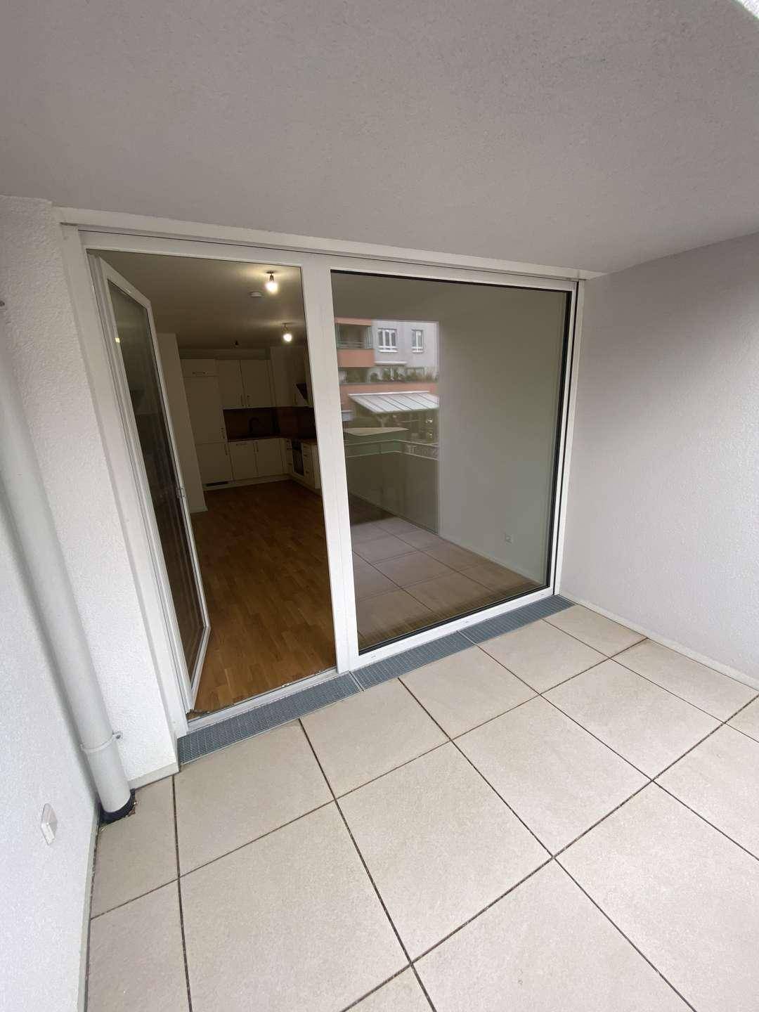 Balkon mit Fliesenboden und Blick durch die offene Balkontür in den hellen Innenraum der Wohnung.