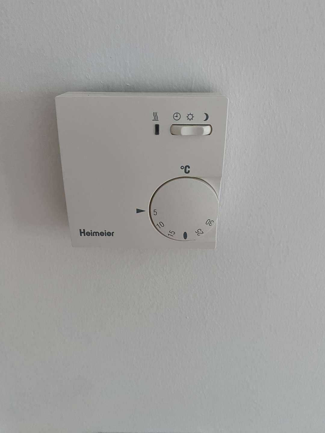Detailaufnahme eines modernen Raumthermostats zur präzisen Temperaturregelung in der Wohnung.
