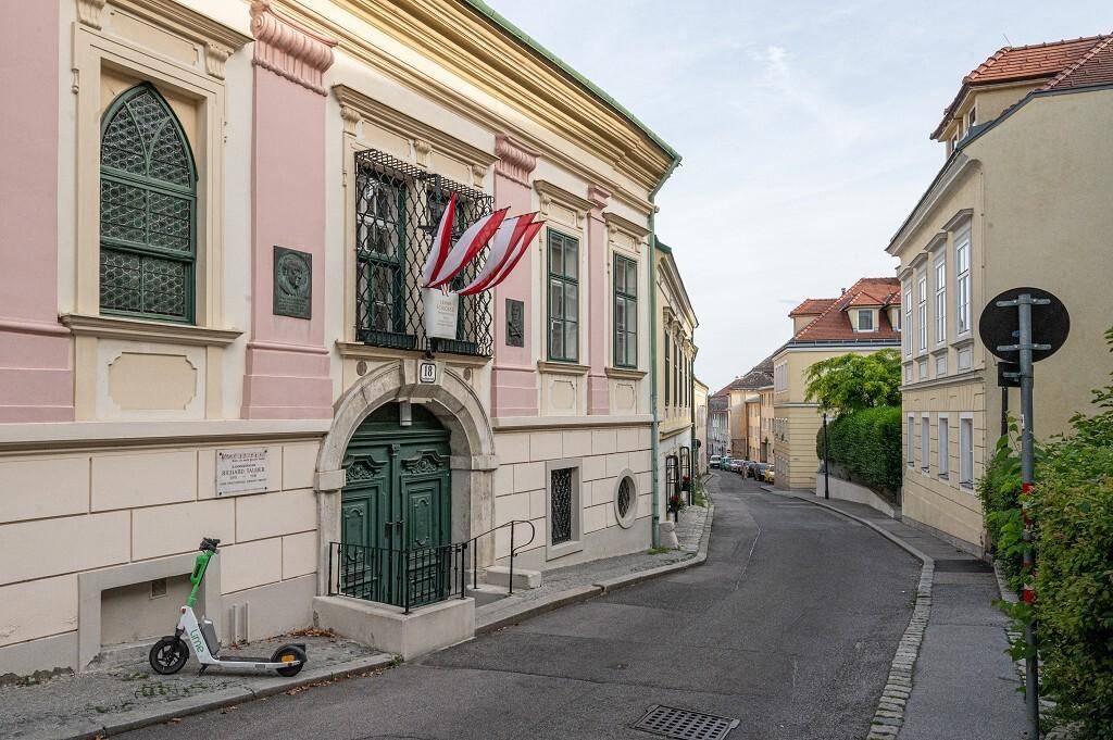 Historisches Gebäude in einer charmanten Gasse mit traditioneller Architektur und österreichischen Flaggen.