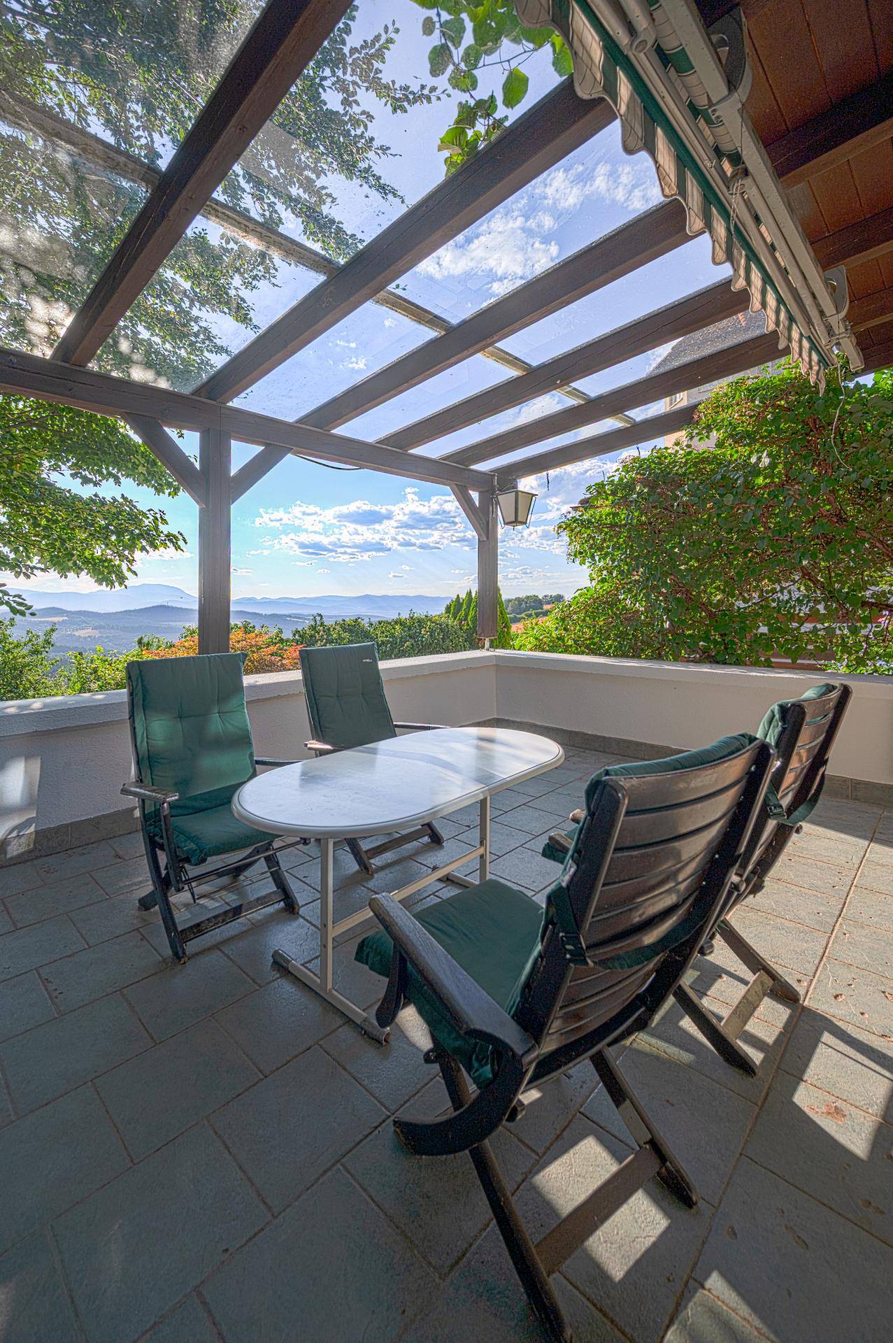 Überdachte Terrasse mit Sitzgelegenheiten und weitem Blick über die Landschaft.