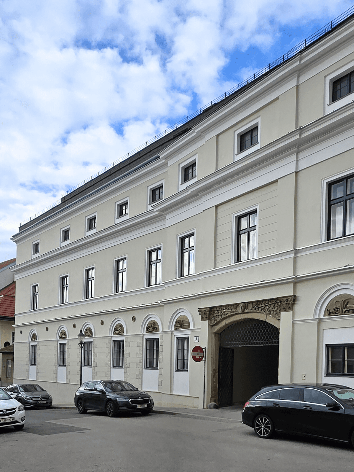 Elegantes historisches Gebäude mit klassischer Fassade und verzierten Fenstern an einer städtischen Straße.