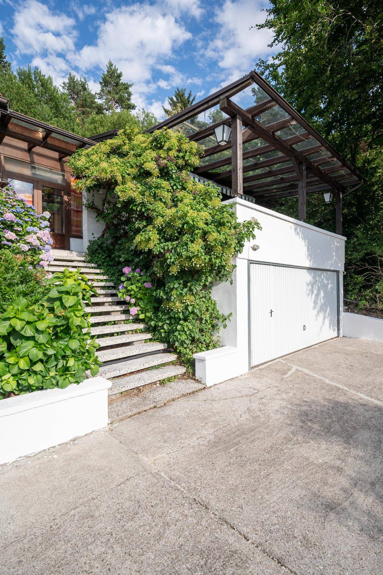 Garageneinfahrt und Treppe, die zum oberen Eingangsbereich des Hauses führt.