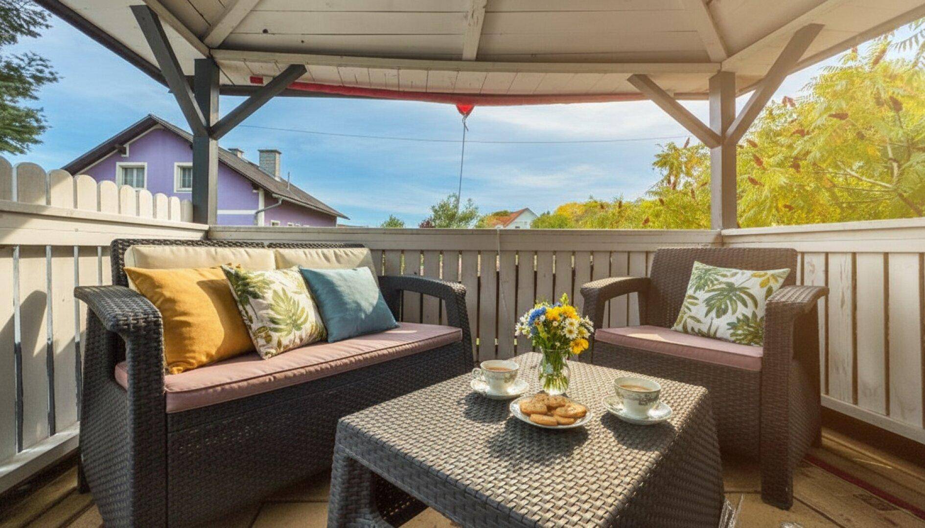 Gemütlicher Sitzbereich im Pavillon mit Korbmöbeln und Blick auf die umliegende Landschaft.