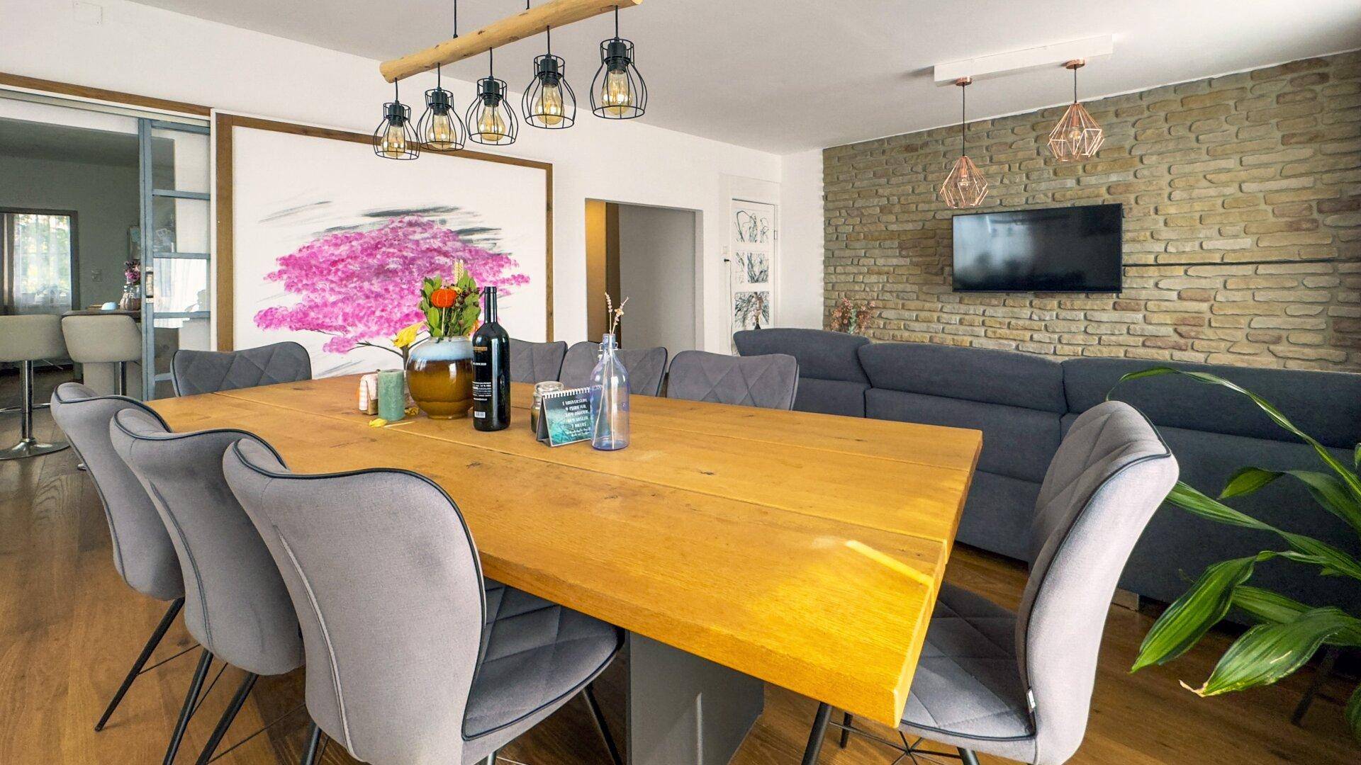 Moderner Essbereich mit Holztisch, bequemen Stühlen und dekorativer Steinwand im Hintergrund.